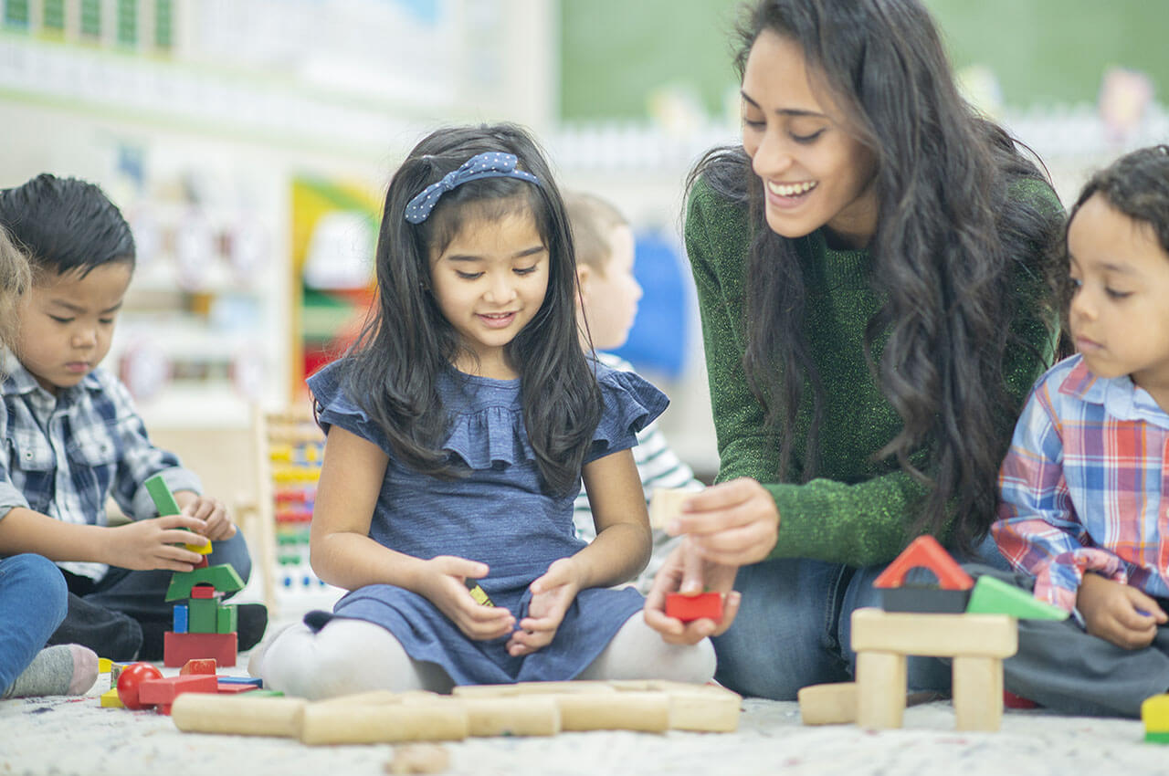 teacher playing with blocks with young children